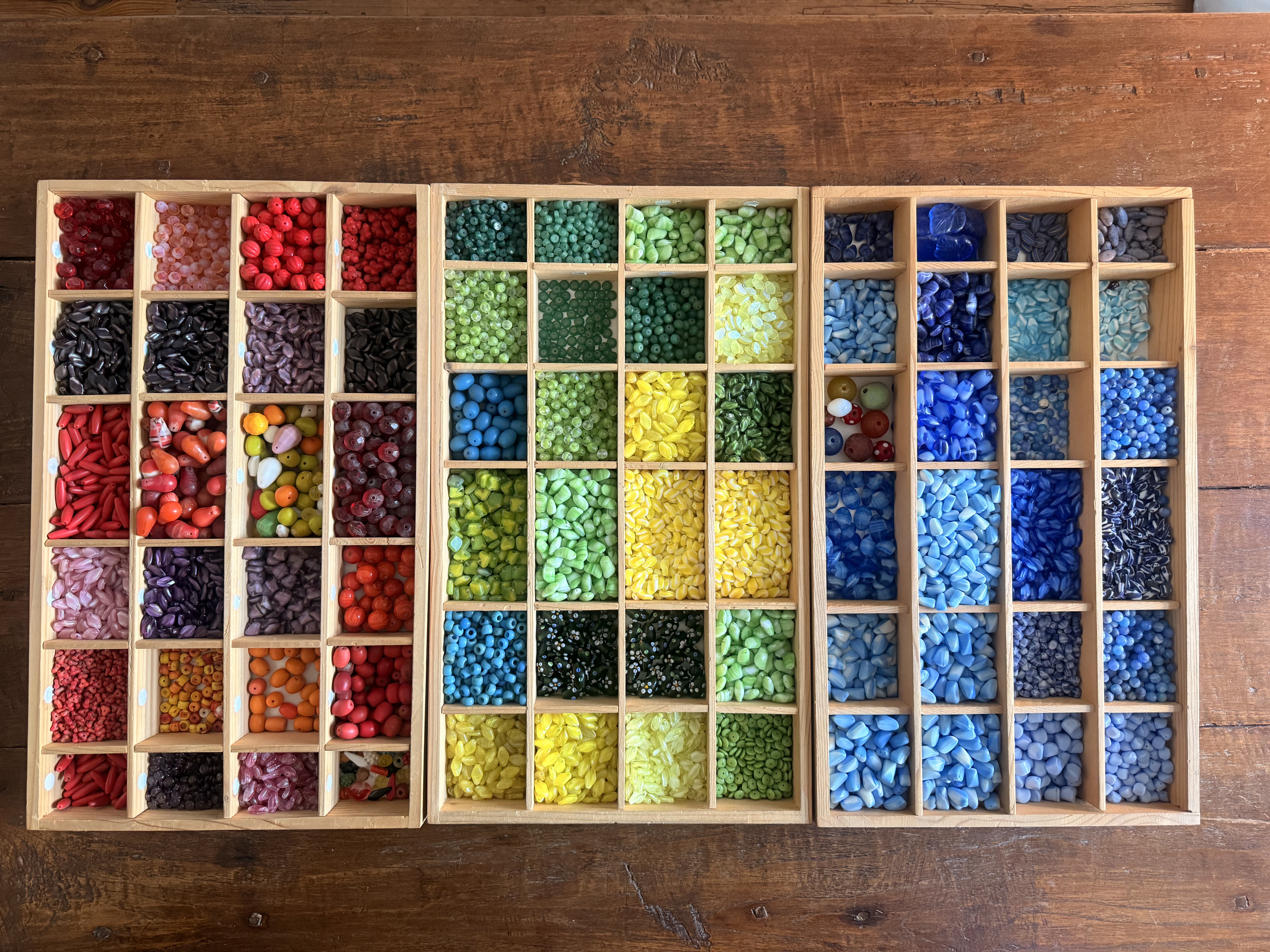 Sorted trade beads arranged in wooden trays.